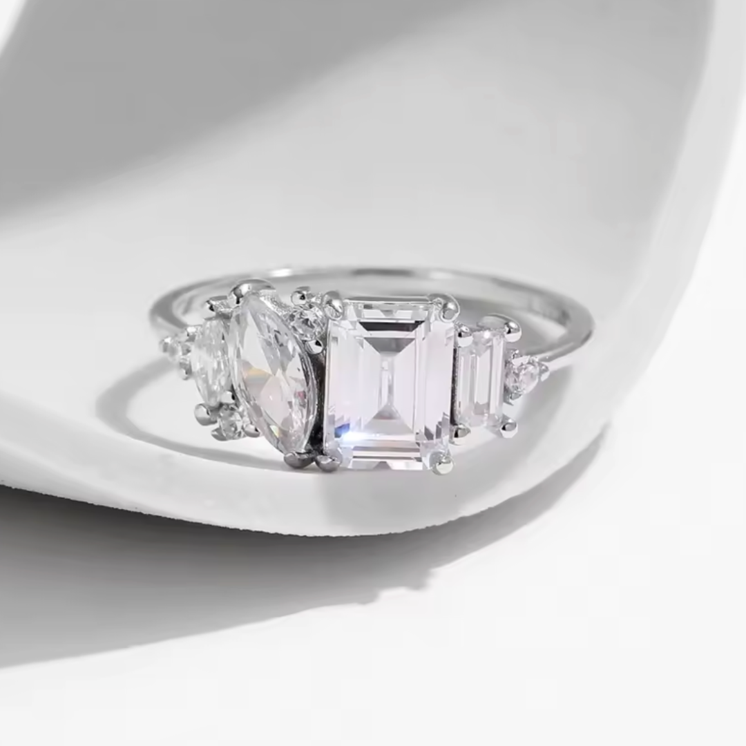 Diamond ring with three clear gemstones on a white background