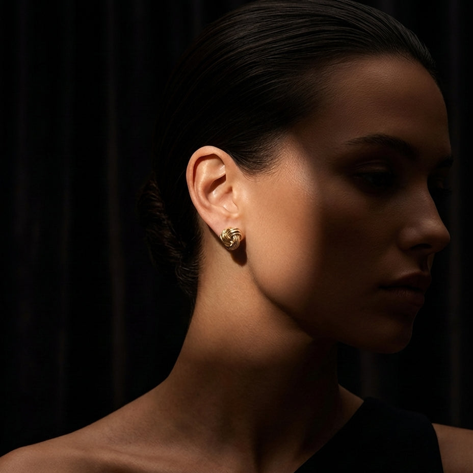 Close-up of a woman wearing gold earrings against a dark background
