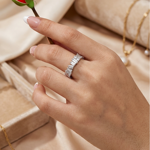 Hand holding a red rose with a diamond ring on a beige fabric background
