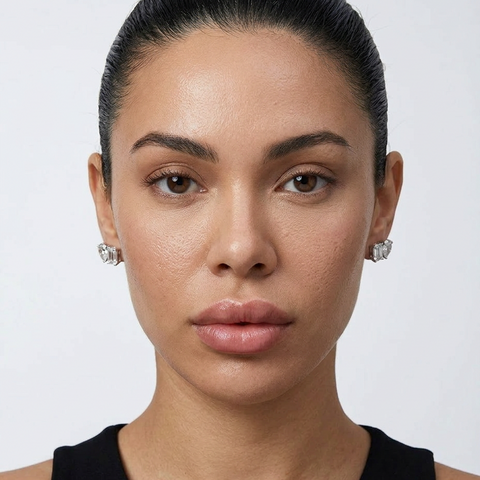 Woman wearing diamond earrings against a plain background